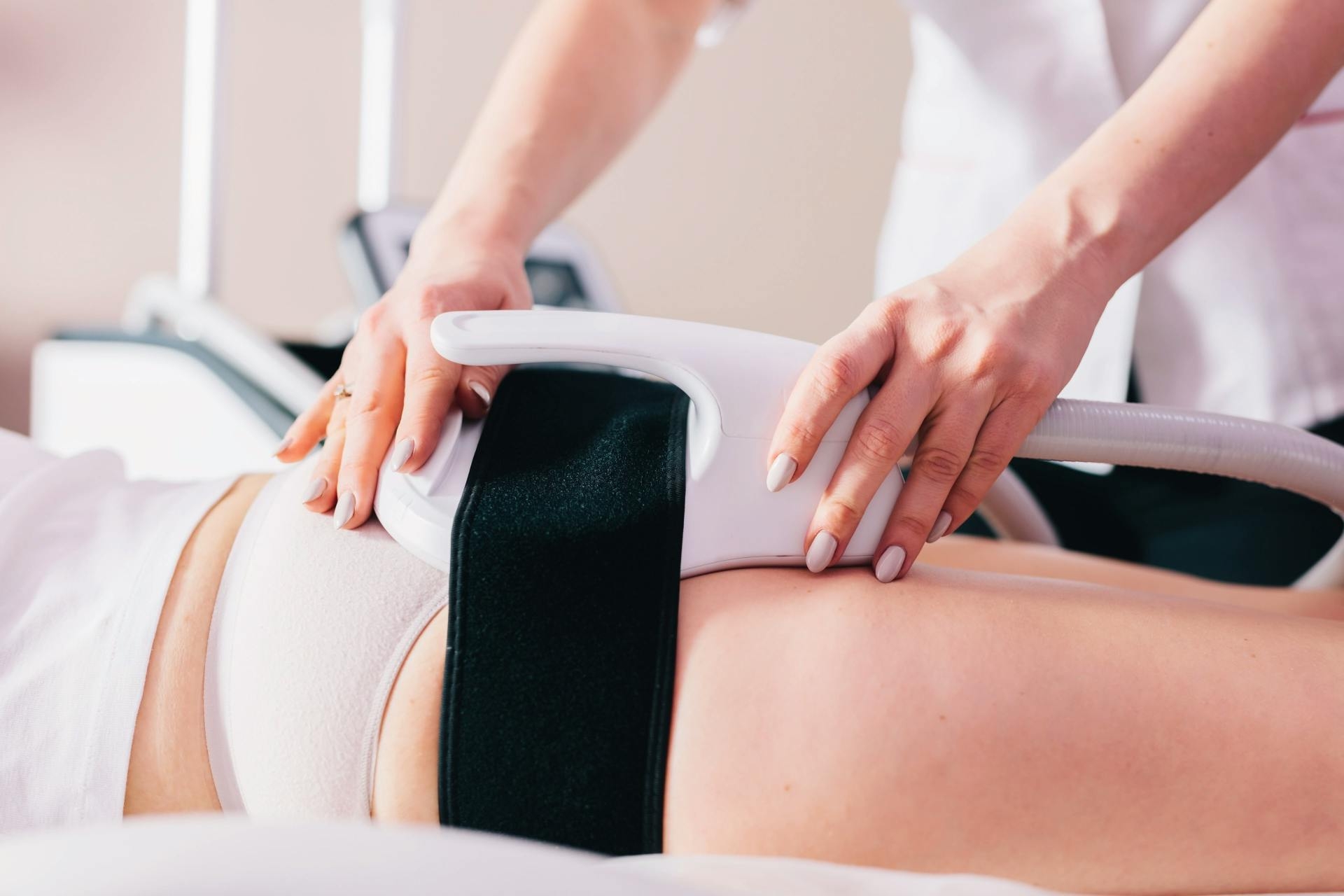 une femme pose un emsculpt sur les fesses d'une patiente